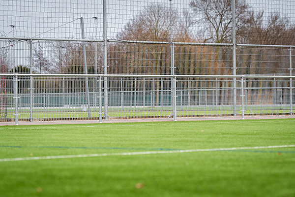 Fencing system at a sporting facility featuring Buisklem brackets, providing a secure perimeter around playing fields.